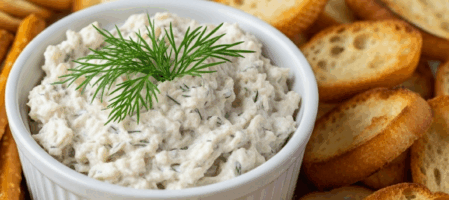 A rustic wooden serving board displays a creamy, pale-colored Midwest-style dip in an earthenware bowl, surrounded by an abundant array of fresh accompaniments. Colorful vegetable crudités including vibrant red and yellow bell pepper strips, crisp celery sticks, orange carrot sticks, and cherry toma
